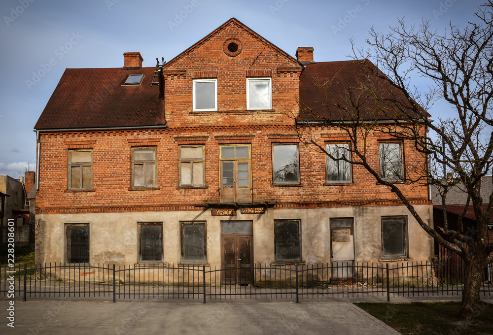 Abandoned old brick building in city center of Kandava, Latvia. Some of the windows are missing and covered by cardboard. Shot in April 2015. Abandoned old brick building in city center of Kandava, Latvia. Some of the windows are missing and covered by cardboard. Shot in April 2015.