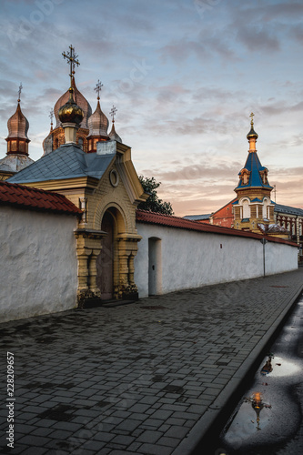 Street view with the monastery of the holy spirit of the Orthodox church in Jekabpils, Latvia at sunset. Church tower reflecting in the puddle.  photo