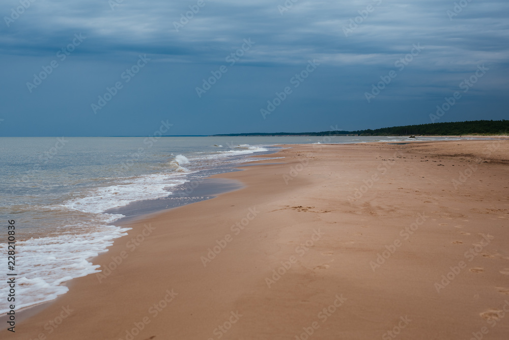 White sand beach with waves and blue sky on cold summer day in Latvia, Pavilosta