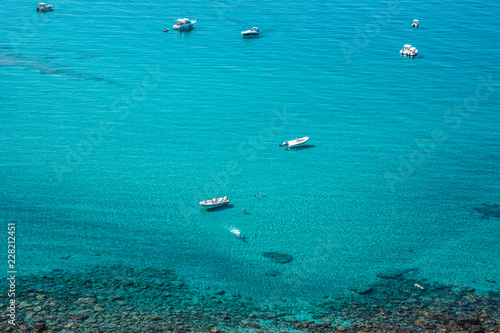 Beautiful turquoise sea and sea shore with few unrecognizable people resting on a sunny summer day. San Giovanni di Sinis, Sinis peninsula, Cabras, Sardinia, Italy.