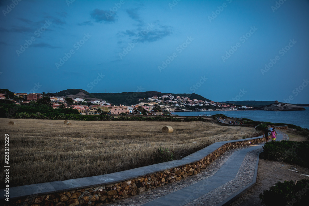 City landscape in the evening with walking path and field visible. Captured in S`Archittu, Oristano province, Sardinia, Italy.