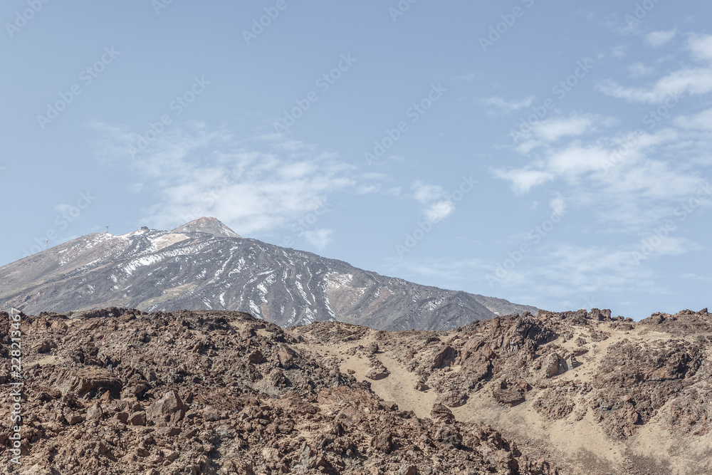 Rocks, lava and Teide volcano in the background in the Teide National Park, Canary Islands, on a sunny day