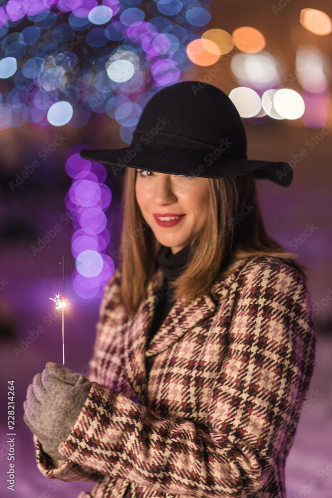 Young girl holding sparklers for christmas during winter alone in the park Young girl holding sparklers for christmas during winter alone in the park