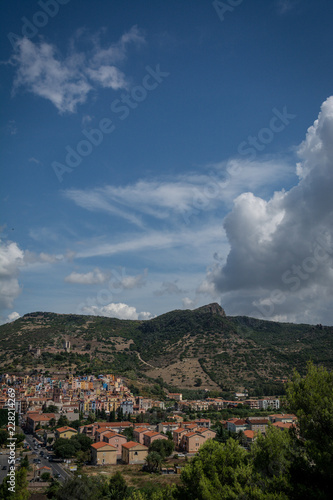 City view of Bosa, Sardinia, Italy from above. Colorful houses, mountains and cumulus clouds on a sunny day. © janaland