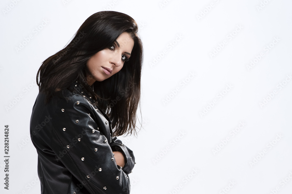 Fashion and Lifestyle Ideas and Concepts. Portrait of Smiling Caucasian Brunette Girl in Rough Leather Jacket Standing Against White. Fashion and Lifestyle Ideas and Concepts. Portrait of Smiling Caucasian Brunette Girl in Rough Leather Jacket Standing Against White.
