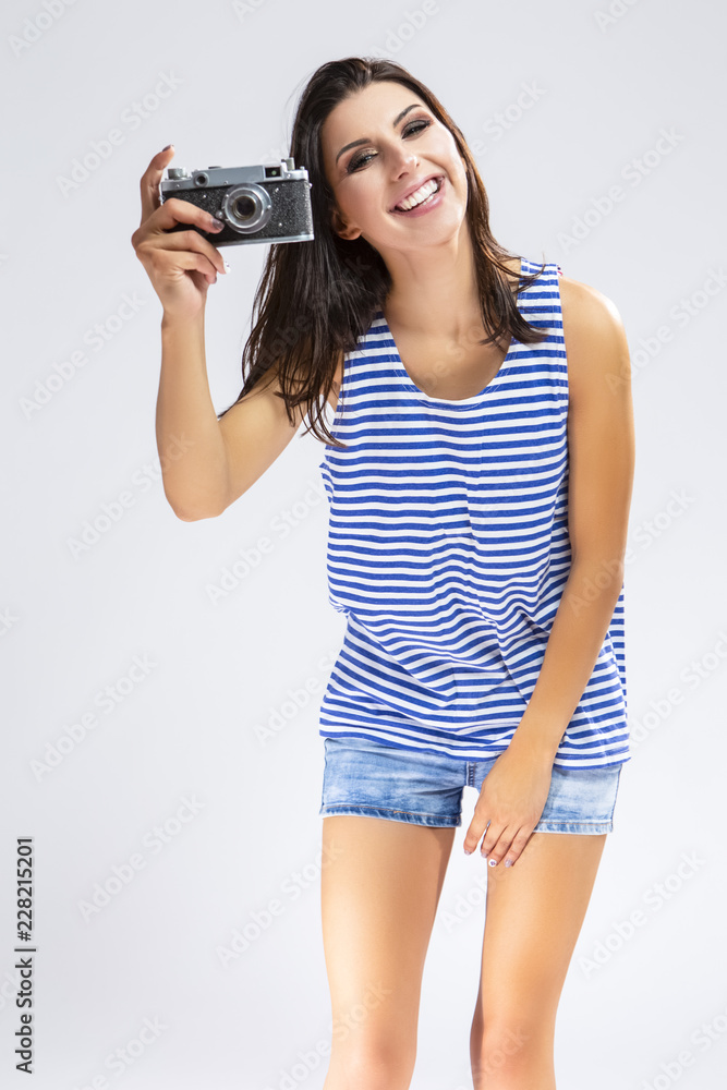 Youth Concepts. Portrait of Happy Caucasian Brunette Girl in Sweatshirt Making Photos with Old Fashioned Film Camera. Posing Against White. Youth Concepts. Portrait of Happy Caucasian Brunette Girl in Sweatshirt Making Photos with Old Fashioned Film Camera. Posing Against White.