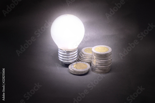 Heap of coins with light bulb