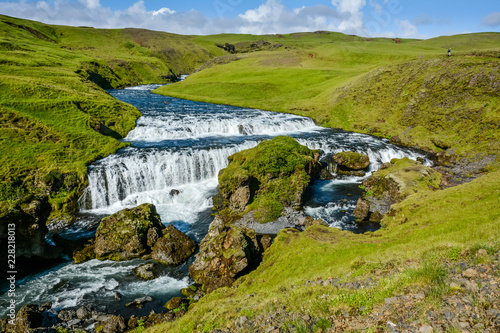 Countryside with trail near famous Skogafoss Waterfall, Iceland on sunny summer day and blue sky