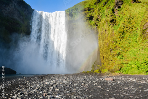Famous Skogafoss waterfall in Iceland with rainbow on sunny summer day  nobody in photo.