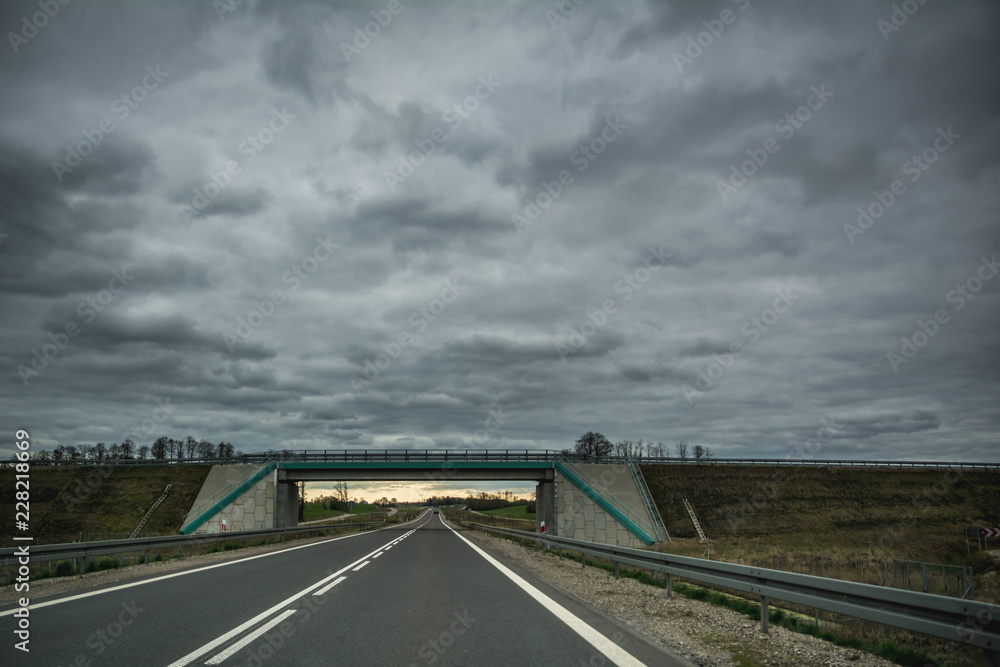 Empty asphalt road and a bridge on overcast summer day in Lithuania