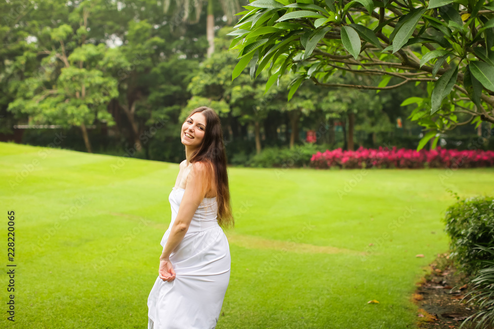 portrait of carefree young woman in white dress posing in green summer park portrait of carefree young woman in white dress posing in green summer park