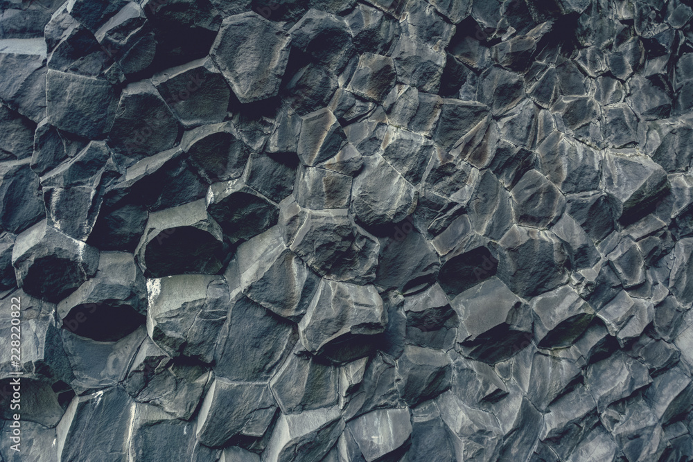 Fototapeta premium Basalt stone columns close-up on Reynisfjara black beach near Vik town, Iceland. Texture and background, vintage effect.