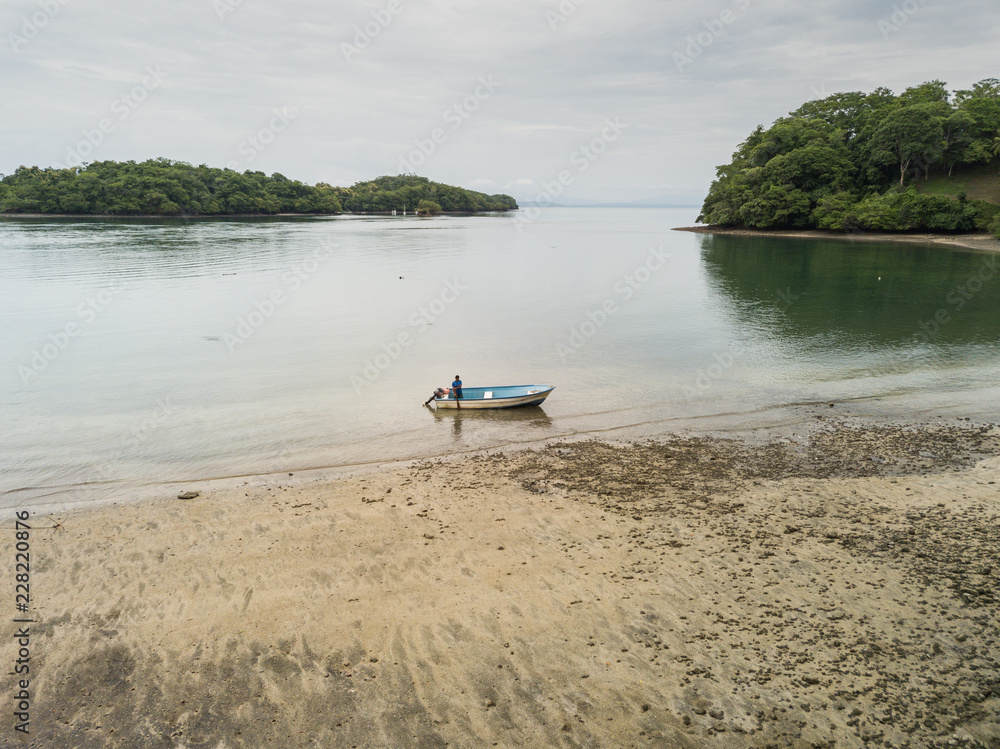 A lone fisherman prepares his small fishing boat to head out into the Gulf of Nicoya from an aerial drone
