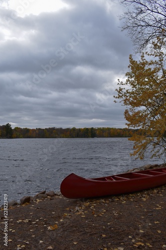Autumn trees around the lake with a red canoe