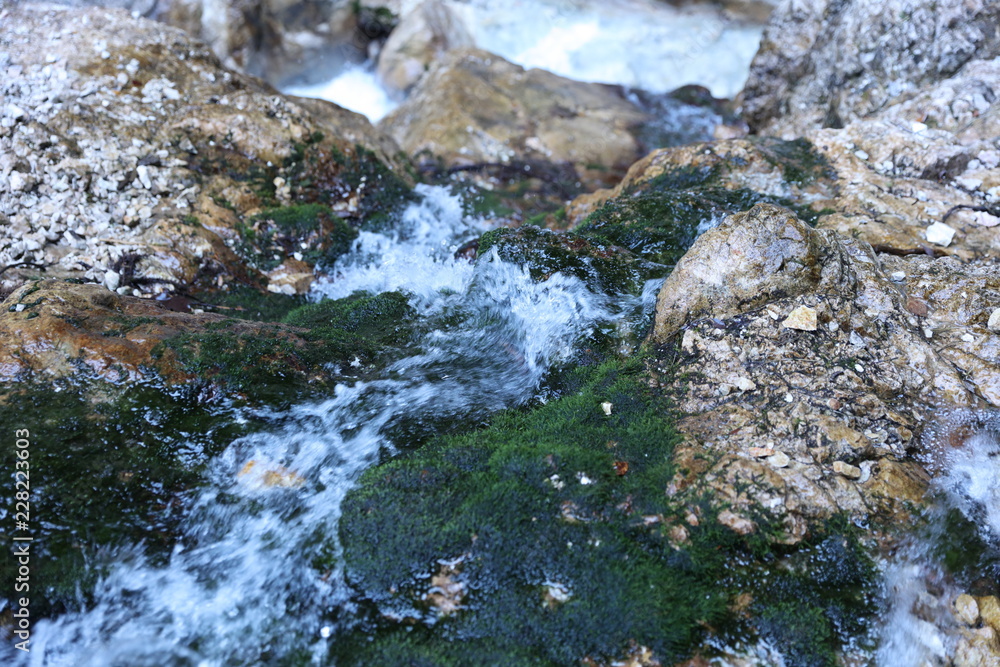 Mountain river water on rocks with green moss Mountain river water on rocks with green moss