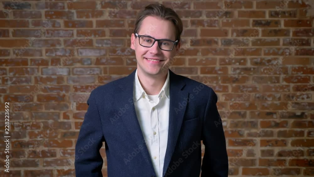 Awesome caucasian man in dark blue suit and glasses standing still and looking straight at camera in red studio isolated Awesome caucasian man in dark blue suit and glasses standing still and looking straight at camera in red studio isolated