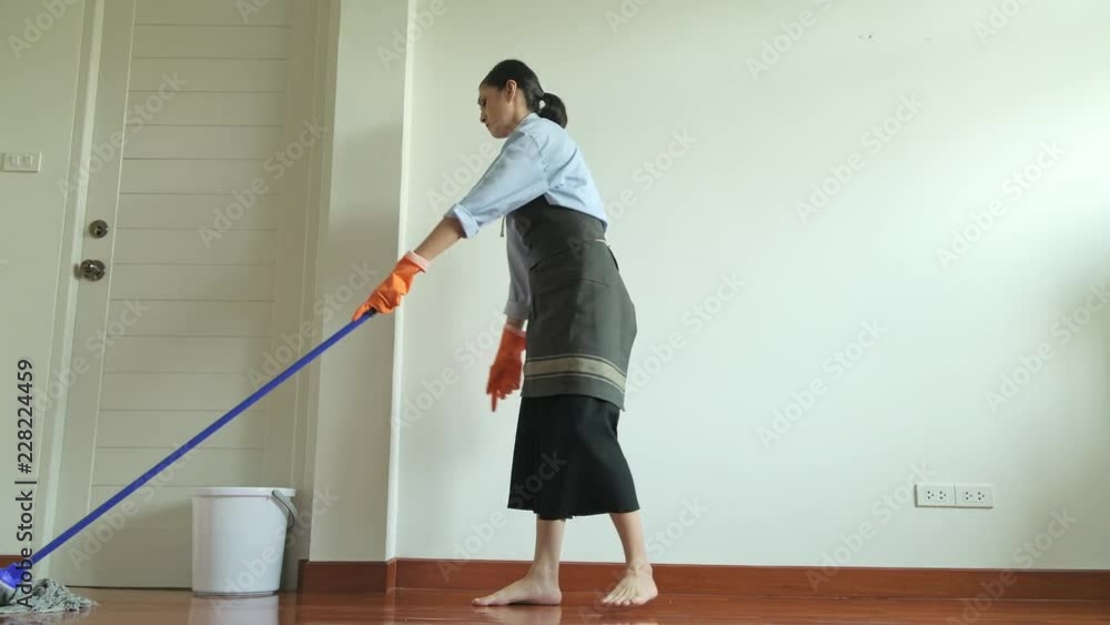 Woman cleaning house with a mop. Beautiful Asian woman cleaning floor with mop. Low angle shot. House cleaning service concept. Woman cleaning house with a mop. Beautiful Asian woman cleaning floor with mop. Low angle shot. House cleaning service concept.