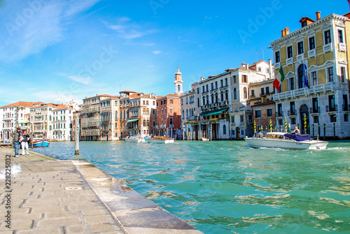 Tourists and a Water Taxi on the Grand Canal in Venice Italy with a Stone walkway in the foreground. 
