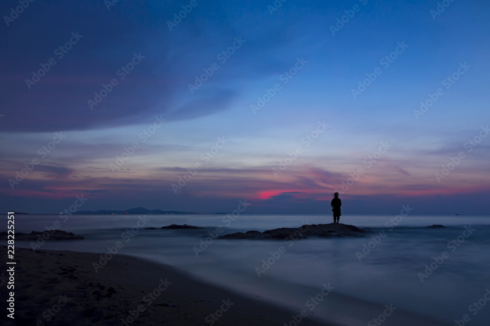 Fototapeta premium Colorful sky over sea and beach with man silhouette.