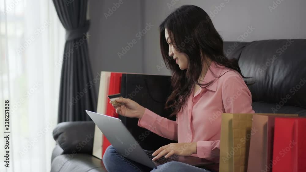 happy woman using laptop computer for online shopping with credit card in the living room happy woman using laptop computer for online shopping with credit card in the living room