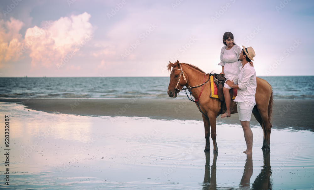 Young couple riding horse on seacoast in summer Young couple riding horse on seacoast in summer