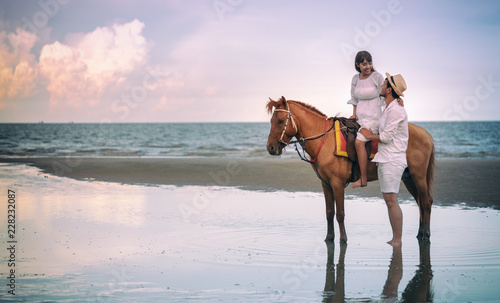 Young couple riding horse on seacoast in summer
