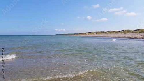 Liseleje Beach by the Tisvilde forest and coastal area on the Danish island of Zealand. A pristine spring morning with a sunny clear blue sky. Shallow water ripples and gentle waves. photo