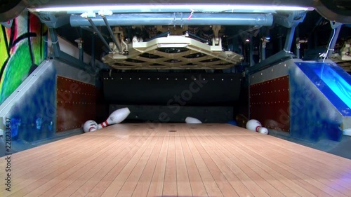 A creative artistic shot follows a blue bowling ball in a dolly shot as the ball hits a strike in high speed in a bowling alley