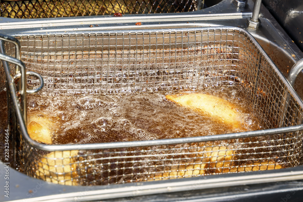 Pies are fried on hot oil in a stainless steel fryer in a street fast food cafe Pies are fried on hot oil in a stainless steel fryer in a street fast food cafe