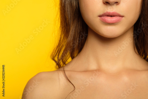 female beauty wellness and health concept. girl with radiant skin and plump sexy seductive lips. cropped portrait of young woman on yellow background.
