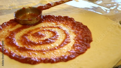 Pouring and speading red sauce on pizza photo