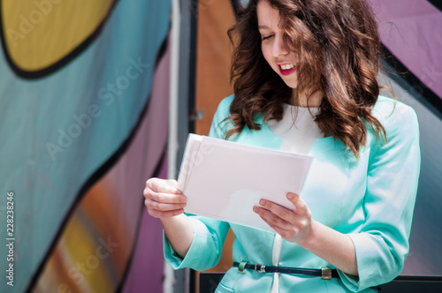 Beautiful young business girl in a blue jacket holds white sheets in hands