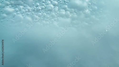 Extremely fast bubbles spinning around and dancing underwater with reflection of lights. photo