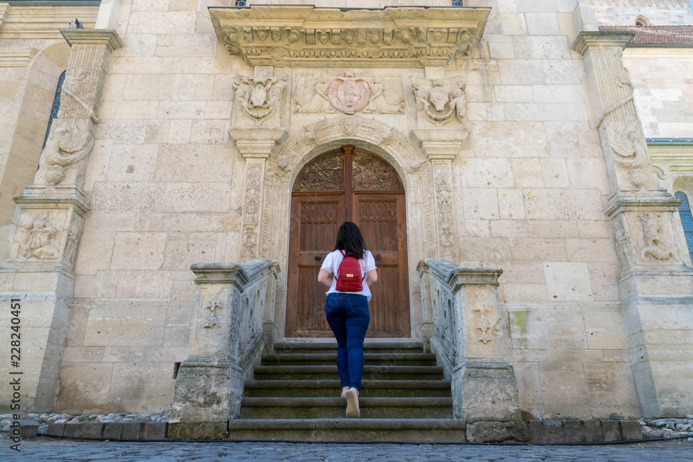 Girl standing in front of the Roman-Catholic Cathedral Saint Michael inside the Citadel Alba-Carolina in Alba Iulia, Romania