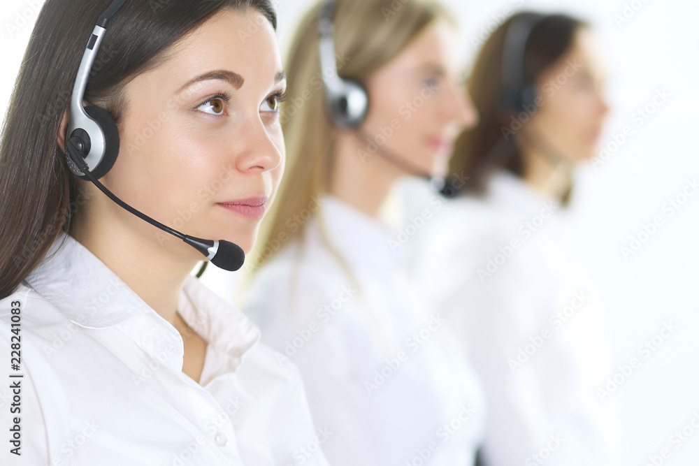 Group of call center operators at work. Focus at beautiful business woman in headset Group of call center operators at work. Focus at beautiful business woman in headset