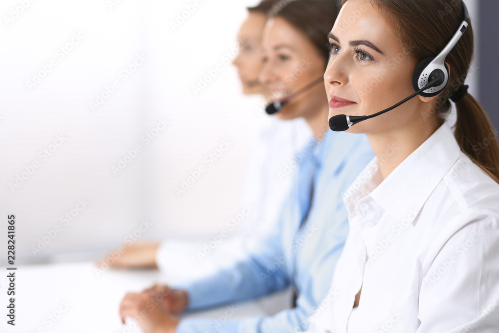 Call center. Group of operators at work. Focus on beautiful business woman in headset Call center. Group of operators at work. Focus on beautiful business woman in headset