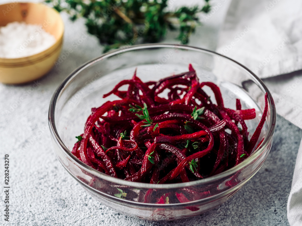 Raw beetroot noodles salad. Vegetable noodles - beet spaghetti in glass plate over gray cement background. Copy space for text. Ideas and recipe for Clean eating, raw vegetarian food concept. Raw beetroot noodles salad. Vegetable noodles - beet spaghetti in glass plate over gray cement background. Copy space for text. Ideas and recipe for Clean eating, raw vegetarian food concept.