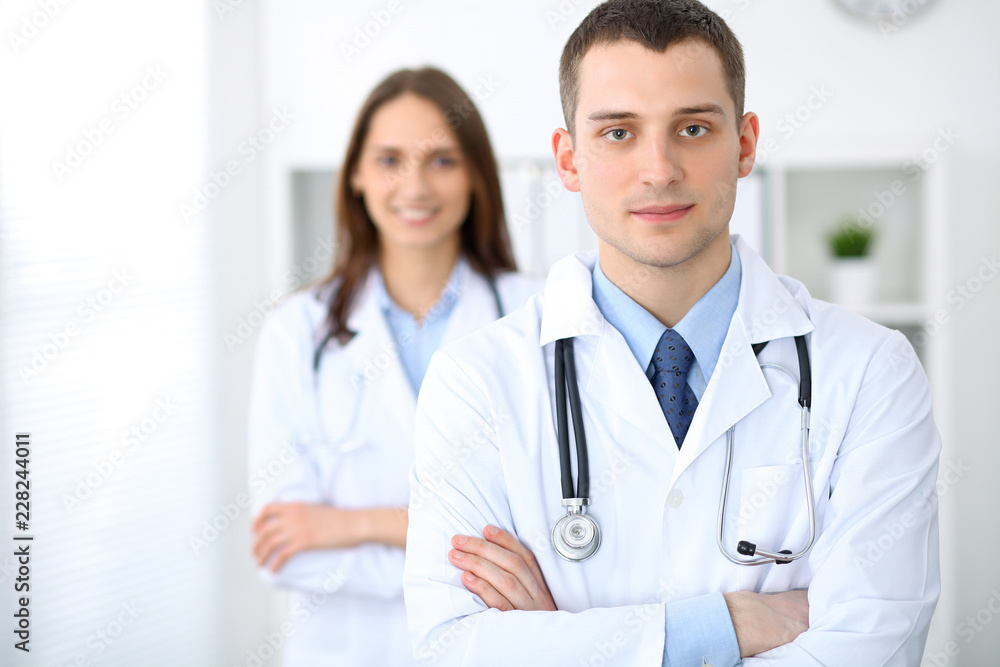 Friendly male doctor on the background of a female physician in hospital office Friendly male doctor on the background of a female physician in hospital office