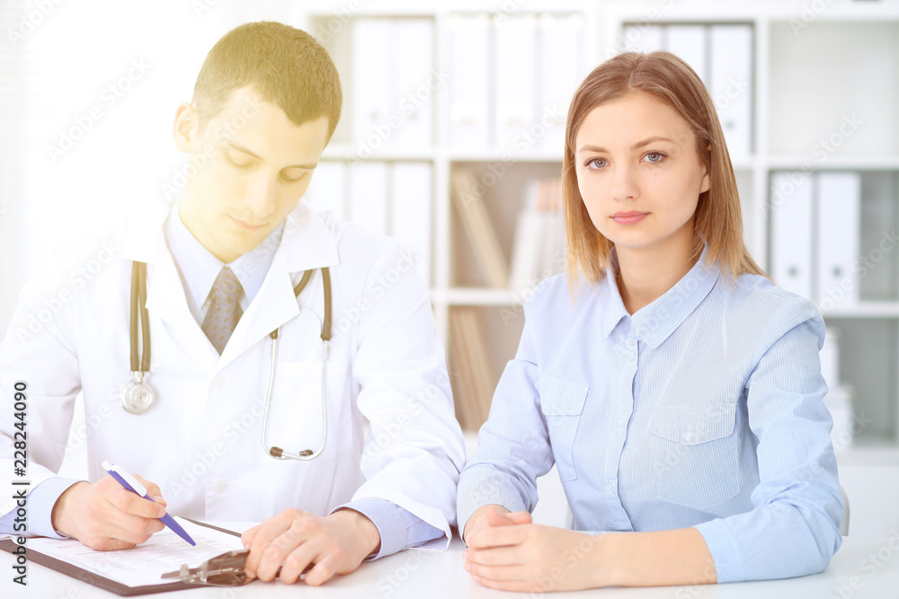 Doctor and patient sitting at the desk. Medicine and health care concept Doctor and patient sitting at the desk. Medicine and health care concept