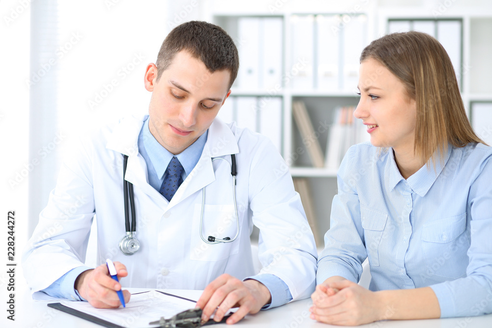 Doctor and patient sitting at the desk. Medicine and health care concept Doctor and patient sitting at the desk. Medicine and health care concept