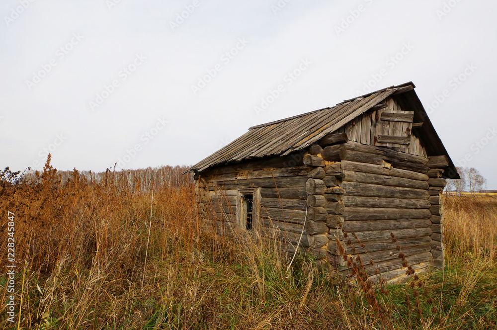 Autumn landscape with a lonely old dilapidated wooden house in the middle of the field Autumn landscape with a lonely old dilapidated wooden house in the middle of the field