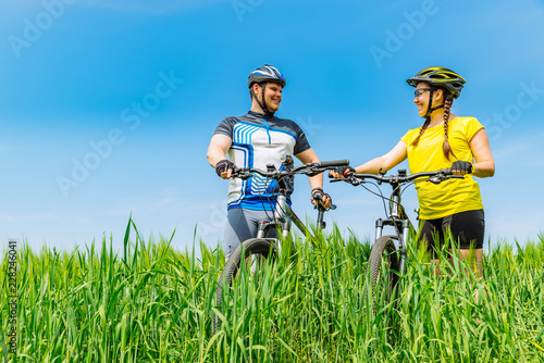 young smiling strong man and woman standing at green field with 