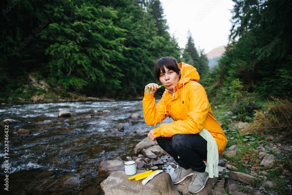 woman cleaning teeth on riverside in mountains woman cleaning teeth on riverside in mountains