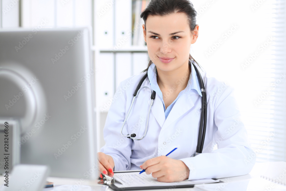 Young brunette female doctor at working place in hospital. Health care, insurance and help concept Young brunette female doctor at working place in hospital. Health care, insurance and help concept