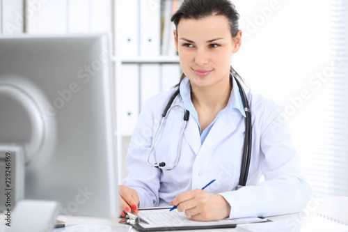 Young brunette female doctor at working place in  hospital. Health care  insurance and help concept