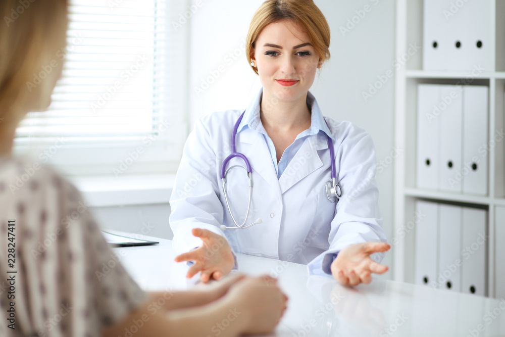 Doctor and patient discussing something while sitting at the desk at hospital. Medicine and health care concept Doctor and patient discussing something while sitting at the desk at hospital. Medicine and health care concept