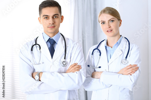 Doctors standing straight with arms crossed in hospital. Physicians ready to help. Concept of healthcare, teamwork and perfect service in medicine