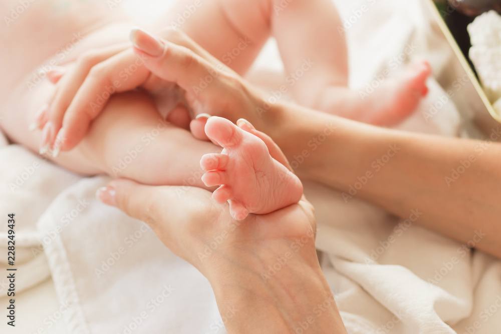 Hands of woman and baby foot, soft focus background