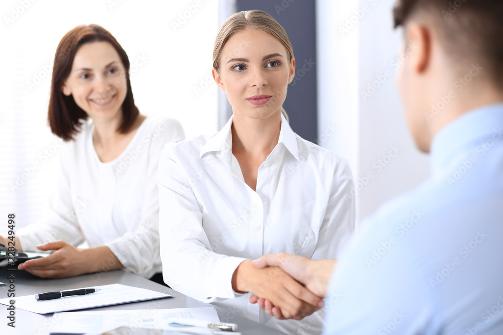 Business handshake by blonde woman and her partner at meeting. Concept of success and agreement Business handshake by blonde woman and her partner at meeting. Concept of success and agreement
