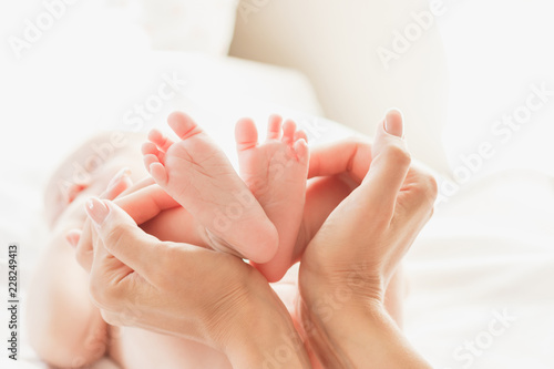 Hands of woman and baby feet, soft focus background